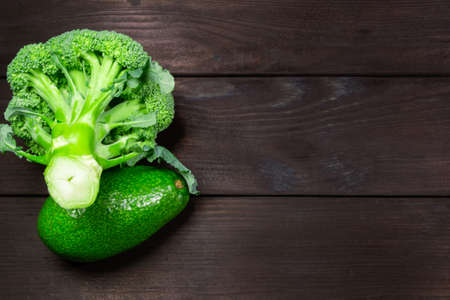 Fresh broccoli and avocado fruit on dark wooden background with space for text. Top view. Concept of healthy, vegetarian, diet food.の写真素材