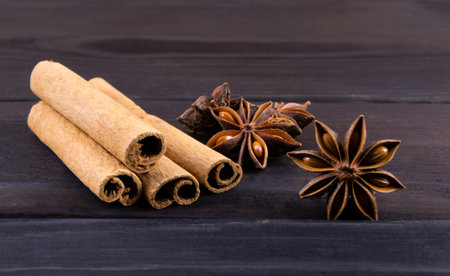 Spice cinnamon sticks and anise on a dark wooden background.