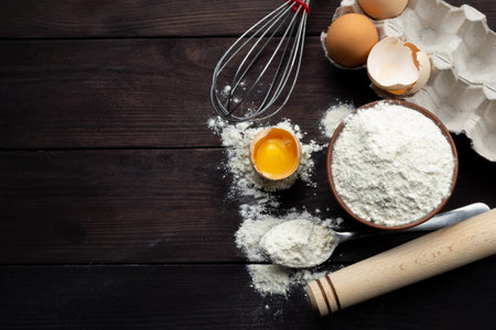 Ingredients for pastries: flour, eggs on a dark wooden background. Space for text. top view.の写真素材