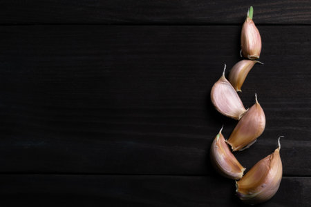 Garlic cloves on dark wood texture. Space for text. top viewの写真素材