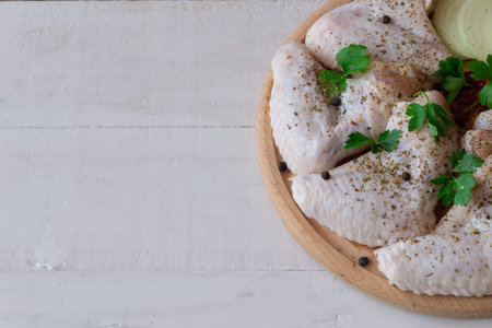 fresh raw middle chicken wings on a wooden board with ingredients. Space for text