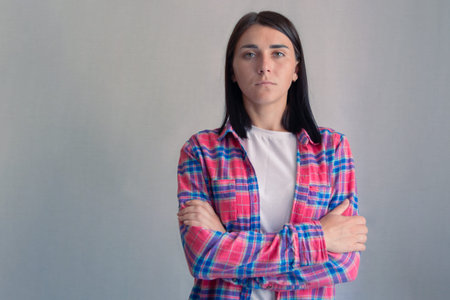Portrait of beautiful brunette hair woman. Serious girl in casual clothes with crossed arms standing...