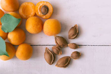 Ripe apricots on rustic background. apricots with leaves and kernels on wooden background. Ripe apricots with copy space for text. Various fresh summer fruits. Apricots on a wooden table. top view.の写真素材