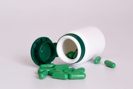 Green pills with pill bottle on a white background with space for text
