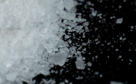 salt crystals are scattered over a black background close-upの写真素材