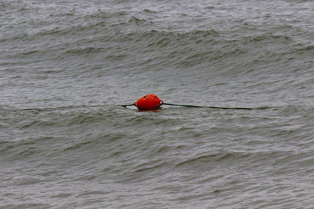 orange buoy on a rope swings on the waves