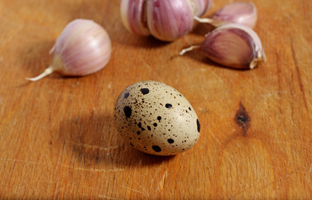 Quail eggs and garlic on a wooden board, close-upの写真素材