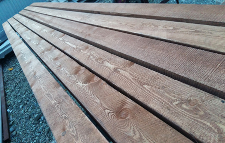 Edged boards of natural wood lie in a row unpolished with burrsの写真素材