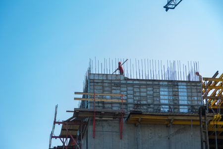 A construction worker stands on the rafters of the upper floor. The builder is installing supports for the concrete.の写真素材