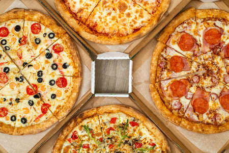 Four different cut pizzas are in square boxes. Meat and vegetarian pizza. Top view.の写真素材