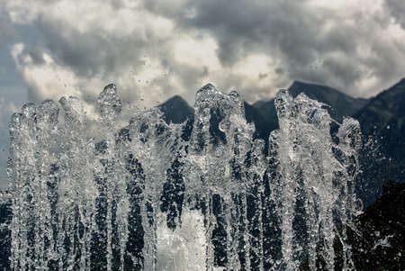 Fountain spray against the background of mountains and cloudsの写真素材