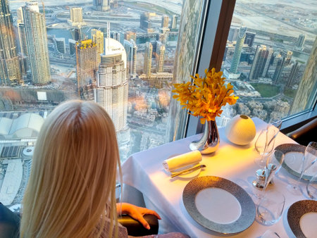 The blonde, waiting for breakfast at a table in a restaurant, looks out the window at magnificent Dubai.の写真素材