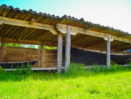 Antique arbor made of natural wood for storing boats on the shore in the summer on a background of green grass,の写真素材