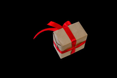Gift box with red ribbon, copy space isolated on black background. Sales concepts, discount price,...