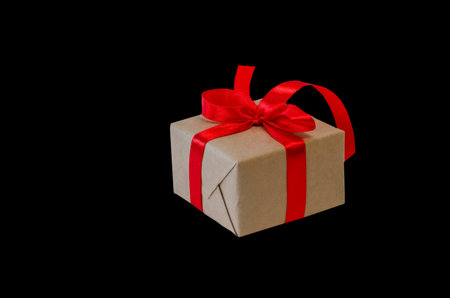 Gift box with red ribbon, copy space isolated on black background. Sales concepts, discount price,...