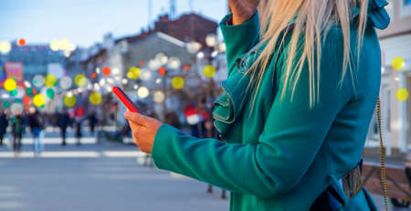 Closeup photo of female hands with smartphone. Night street, bokeh lightの写真素材