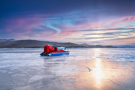 Colorful sunlight outside the mountain peaks is reflected on the ice of frozen Lake Baikal at sunset, winter landscape, cold feelingの写真素材