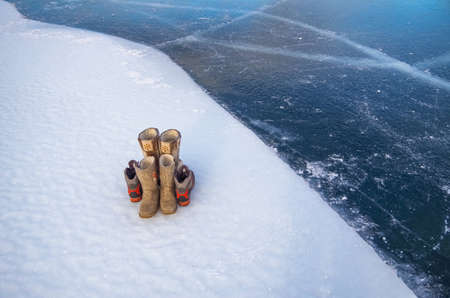 Winter shoes. In the snow on the ice there are high fur boots, felt boots and warm bootsの写真素材