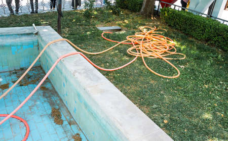 hose irrigation equipment on green grass near an empty swimming pool.の写真素材
