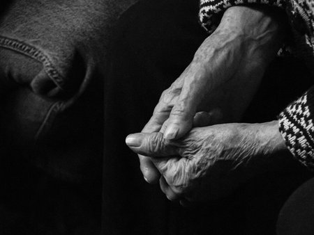Hands of an elderly woman on a black background, the concept of old age. Black and white photo.の写真素材