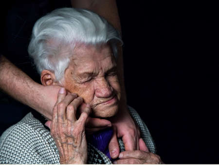 Hands of an elderly woman against black background.の写真素材