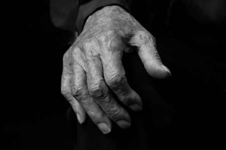 Hands of an elderly woman on a black background, the concept of old age. Black and white photo.の写真素材