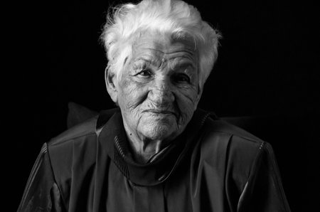Portrait of serious senior woman against black background. Black and white photo.