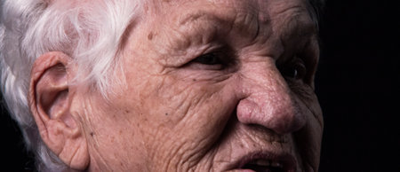 Portrait of an aged woman looking away on a black backgroundの写真素材