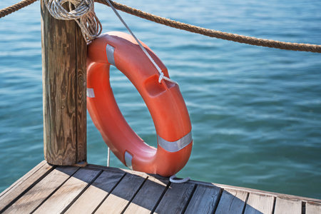 Red lifebuoy near the fence on the wooden pier.