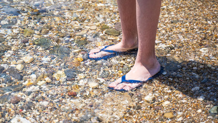 Mens feet in sandals on the beach.