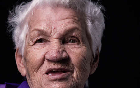 Portrait of an aged woman looking away on a black backgroundの写真素材