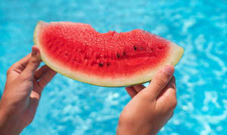 piece of watermelon in female hands at the pool