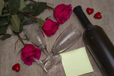 Roses are red hearts with a dark bottle of wine and glasses on grey backgroundの写真素材