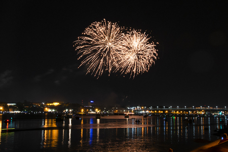 Salute of many orange yellow fire bursts on the background of the night Kostroma and reflection in the river surface of the Volga riversの写真素材
