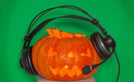 Musical pumpkin to advertise outstanding radio with glowing eyes in headphones for the Halloween holidayの写真素材
