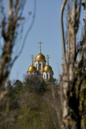 the church is visible through the trees, three golden domes, cloudless skyの写真素材