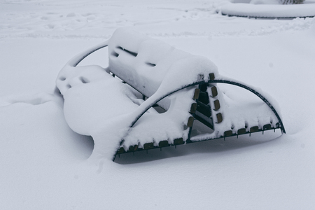 A photo of a bench in a winter park. An empty, lonely bench marked by a snowdrift.の写真素材