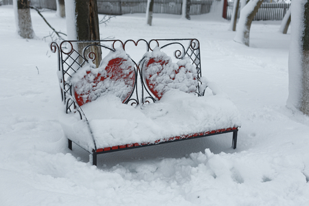 A photo of a bench in a winter park. An empty, lonely bench marked by a snowdrift.の写真素材
