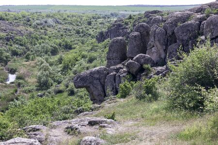 Photo landscape Aktovskogo canyon in Ukraine. Granite cliffs overgrown with green trees with a river flowing below.の写真素材
