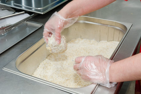The cook fries meat in a deep fryer. Preparation in a deep fryer