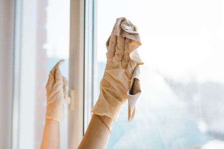 The woman washes a window. The young woman cleans dirt from a window. Pure windows in the house.の写真素材