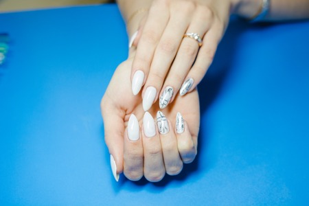 Manicure. The woman cleans and paints nails. The woman processes nails on hands a varnish. Shelak. Gel, a varnish, placing acryle on nails. Salon for manicure.の写真素材
