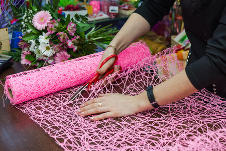 people, business, sale floristics - wrapping up a sheaf in paper in flower shop