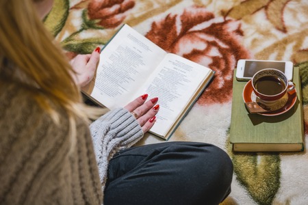 The girl reads the book and has coffee. Rest and reading house. Read to a hobby books.の写真素材