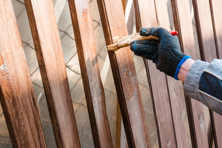 To paint a fence. The man paints a fence. To paint with a board brush.の写真素材