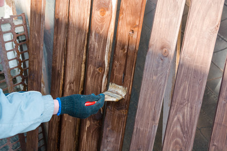 To paint a fence. The man paints a fence. To paint with a board brush.の写真素材