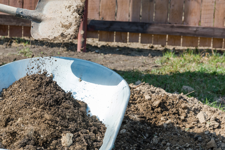 Garden wheelbarrow with the earth. To fill the earth in a wheelbarrow for construction.の写真素材