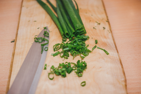 To cut green onions. The girl cuts green onions on a wooden board. Healthy foodの写真素材
