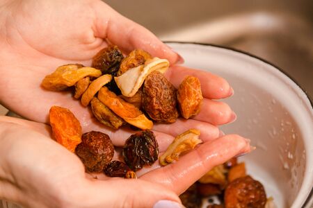 The girl washes dry fruit with water. Dry fruit in hands.の写真素材