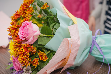 The girl the florist makes a bouquet of flowers. The florist does a bouquet. Paper for flowers.の写真素材
